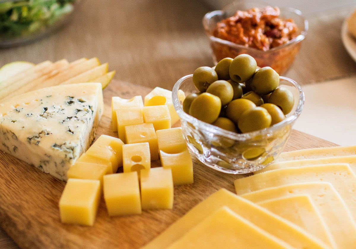 Zoete olijven met kaasblokjes op een plank | Kaas & Borrelz