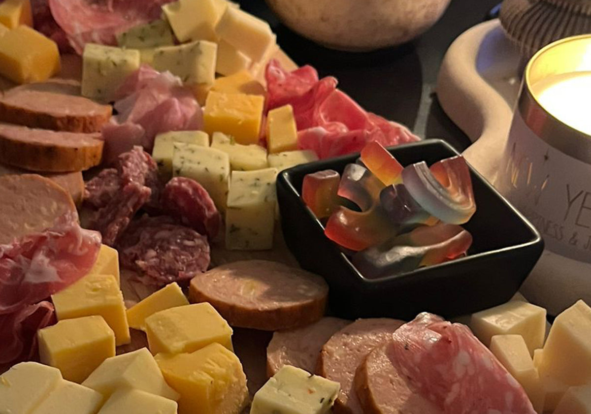 Borrelplank met kaasblokjes, worst en snoep bij kaarslicht | Kaas & Borrelz